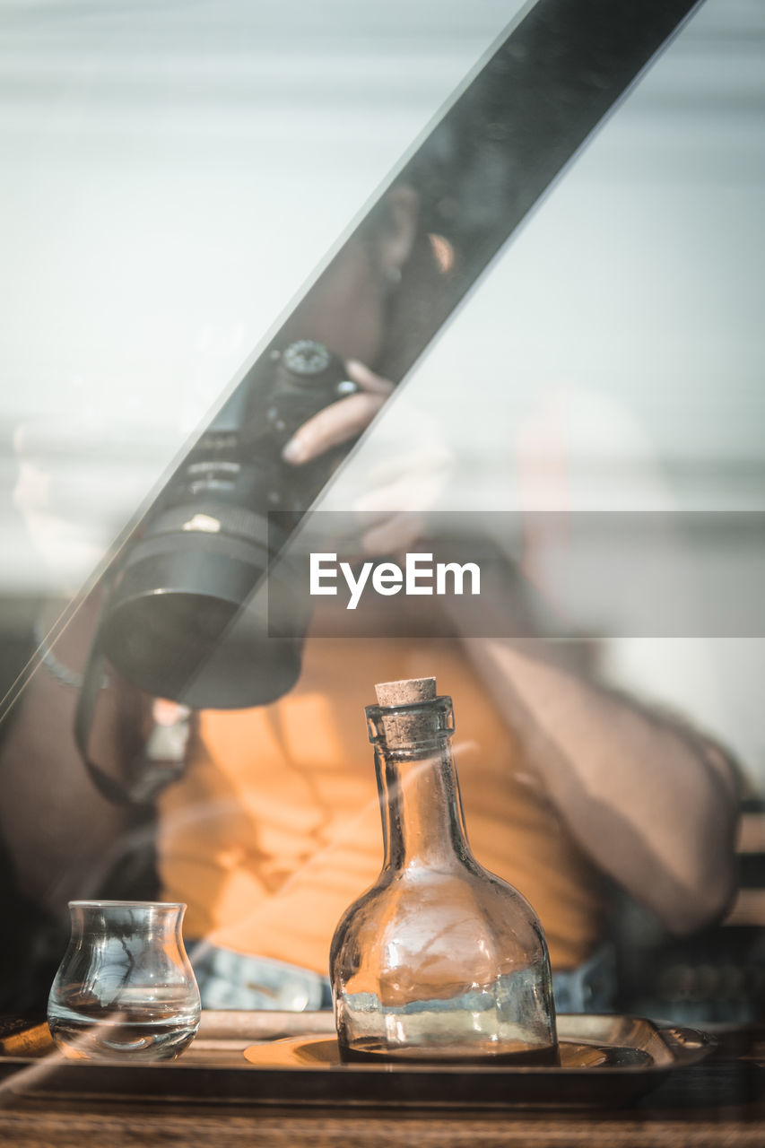 Woman photographing cup seen through window