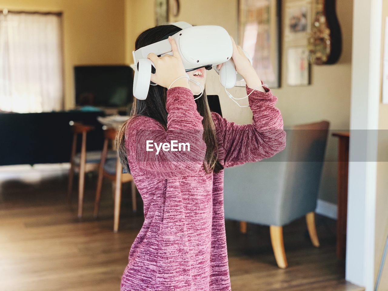 Young woman standing at home playing vr