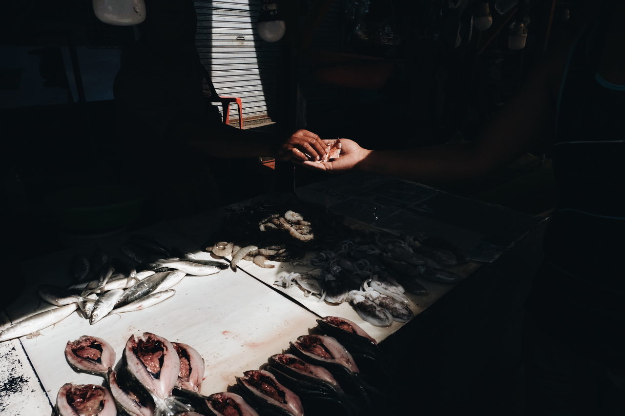 Cropped hand of person giving money to vendor while buying fish at market