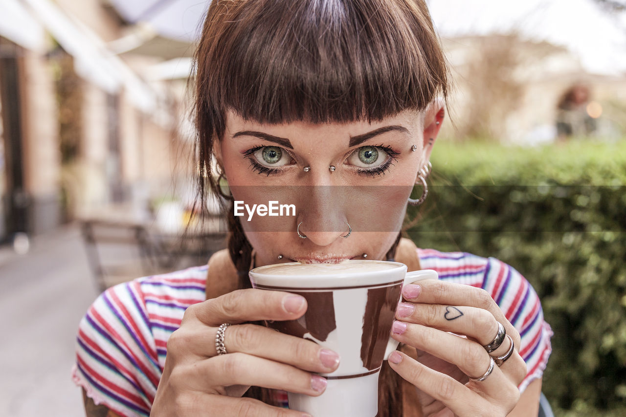 Portrait of young woman drinking coffee at outdoor cafe