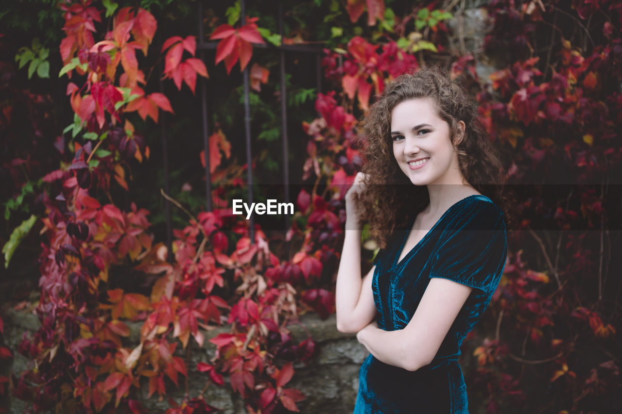 Beautiful curly hair girl in a dark blue velvet dress in an autumn park