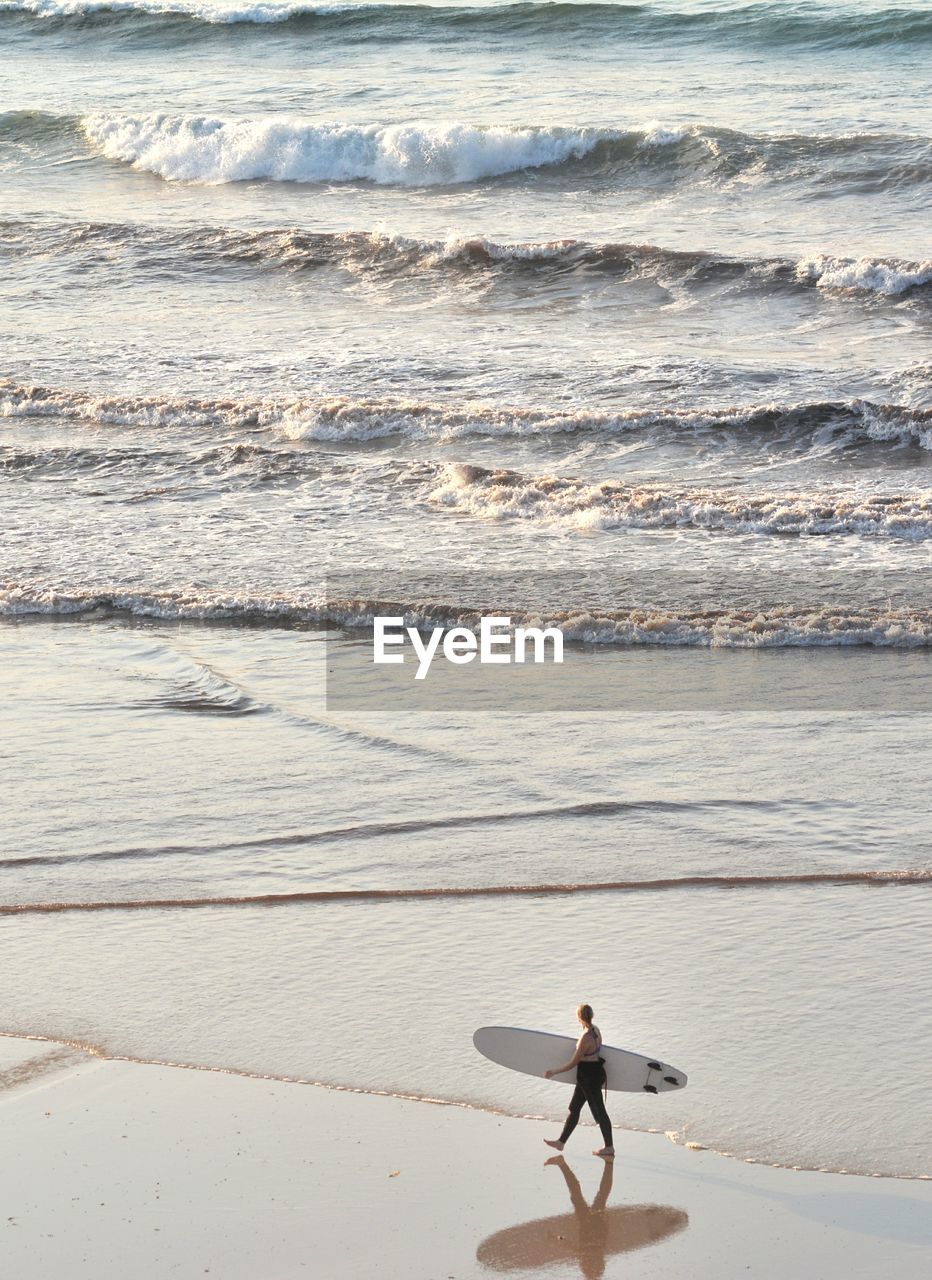 FULL LENGTH OF MAN SURFING ON SEA SHORE