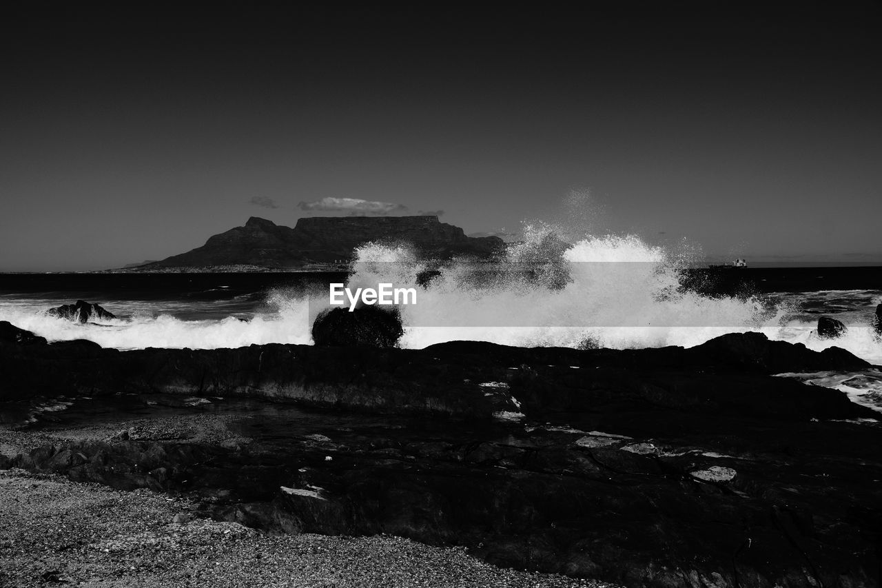 SCENIC VIEW OF WAVES SPLASHING ON SHORE AGAINST SKY