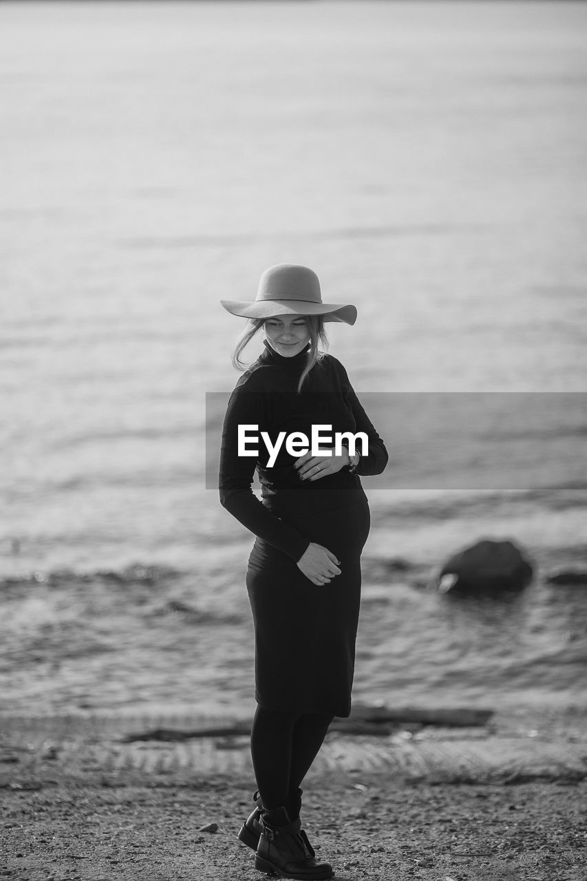 Beautiful young pregnant woman in a black turtleneck and black tight skirt, a classic beige hat 