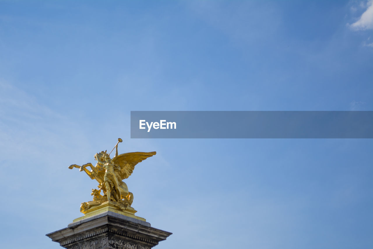 LOW ANGLE VIEW OF STATUES AGAINST BLUE SKY