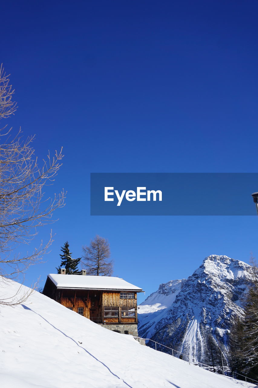 SNOW COVERED HOUSES AGAINST MOUNTAIN RANGE