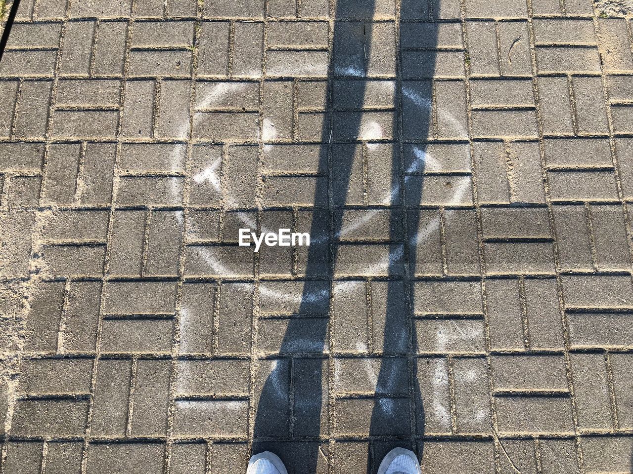 SHADOW OF PERSON ON FOOTPATH
