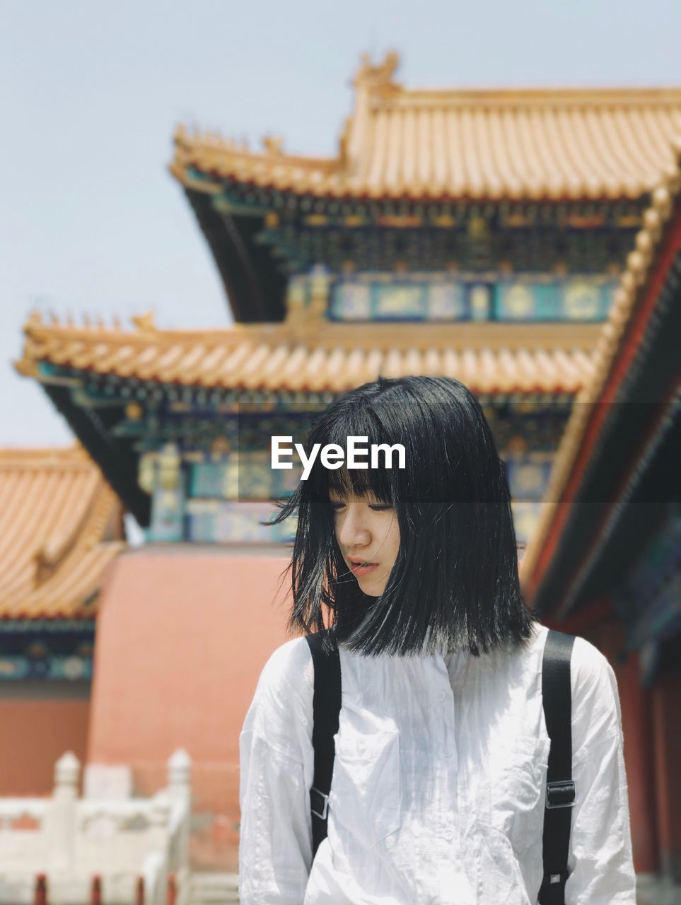 REAR VIEW OF YOUNG WOMAN STANDING AGAINST TEMPLE