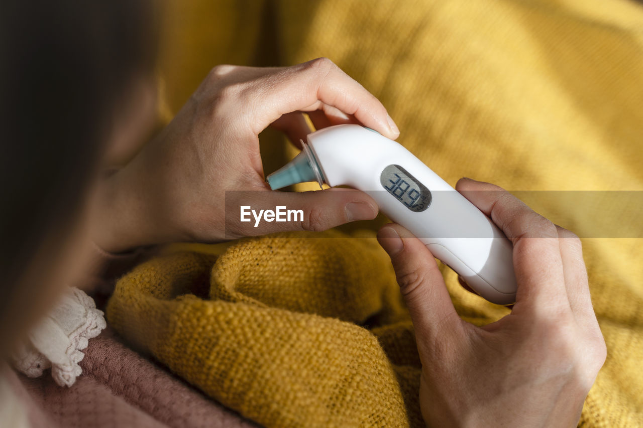 Woman checking temperature with thermometer at home