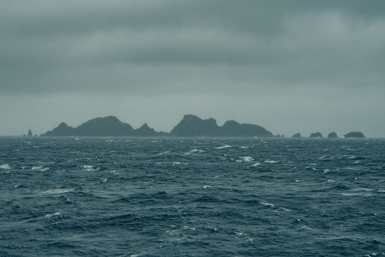 SCENIC VIEW OF SEA BY MOUNTAIN AGAINST SKY