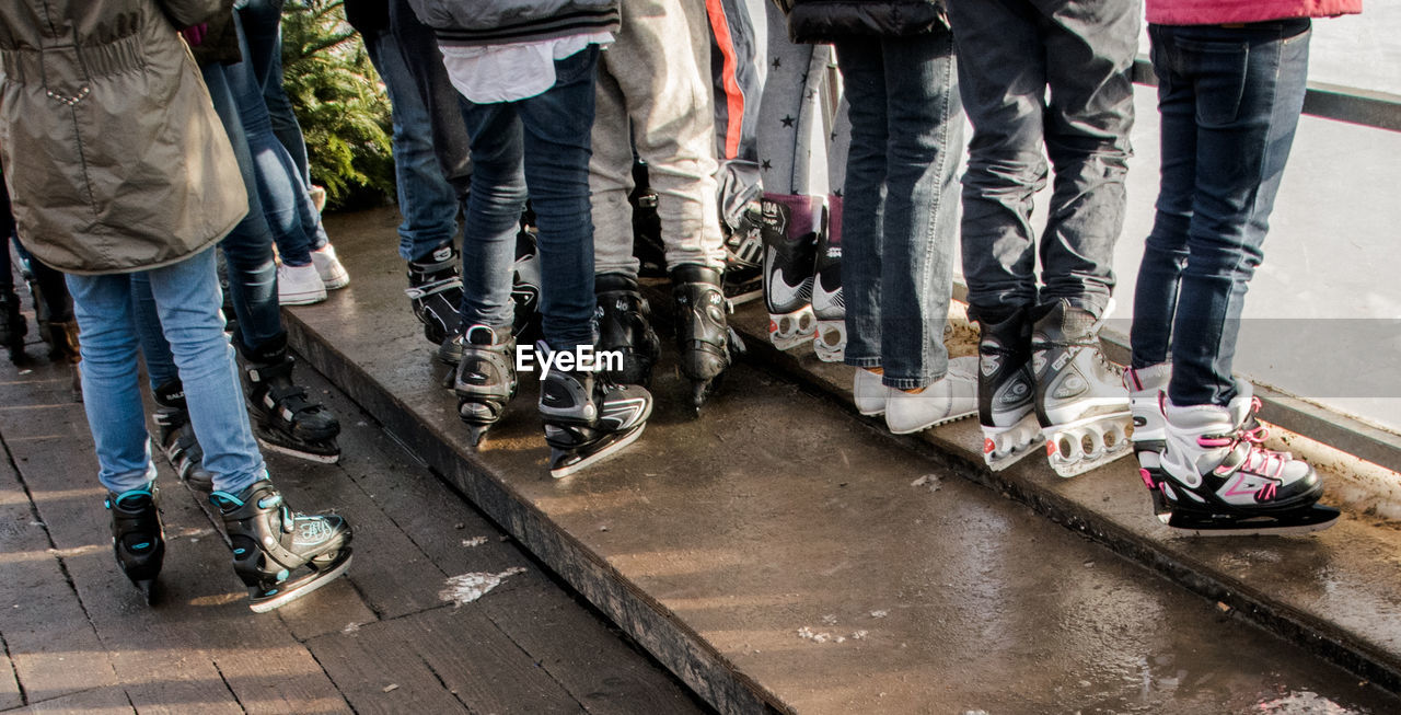 Low section of ice skaters standing outside ice rink