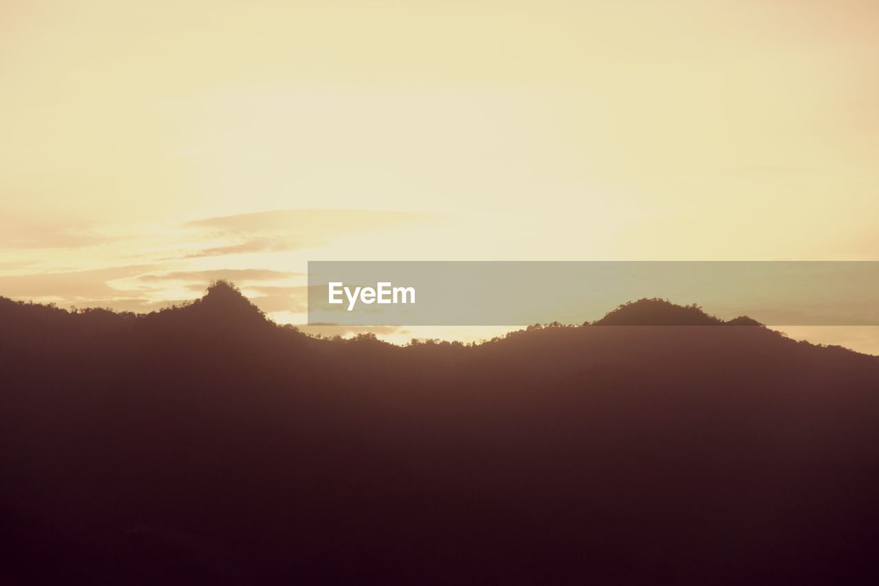SCENIC VIEW OF SILHOUETTE MOUNTAINS AGAINST SKY AT SUNSET