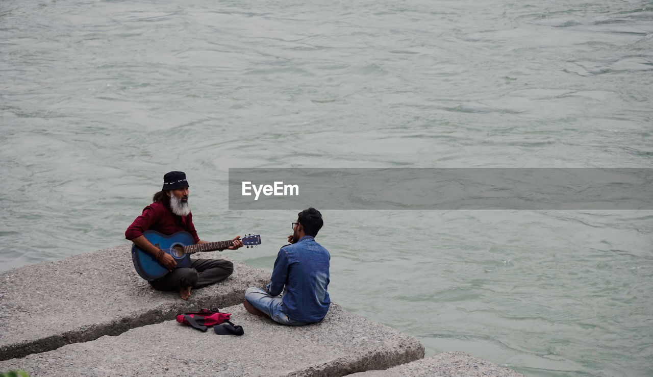 HIGH ANGLE VIEW OF FRIENDS SITTING IN SEA