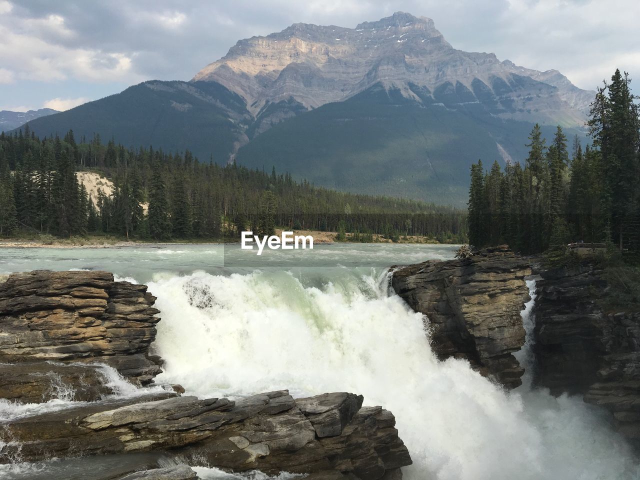 SCENIC VIEW OF WATERFALL IN MOUNTAINS AGAINST SKY