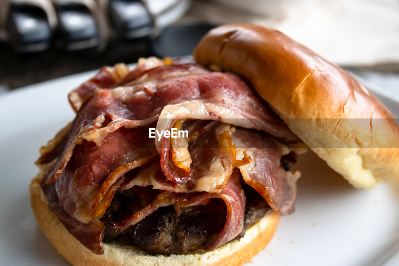 Many strips of bacon on a burger on a plate close up