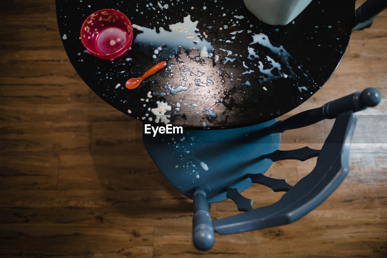 Big mess of spilled milk and cereal on table with empty bowl and spoon