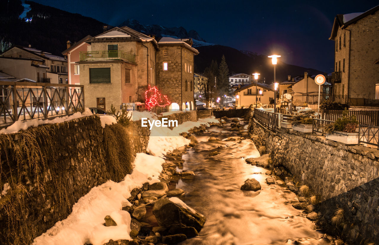 STREET AMIDST ILLUMINATED BUILDINGS DURING WINTER