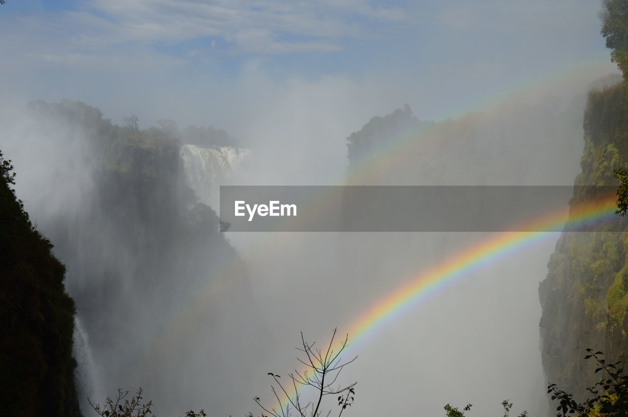 RAINBOW OVER MOUNTAIN AGAINST SKY