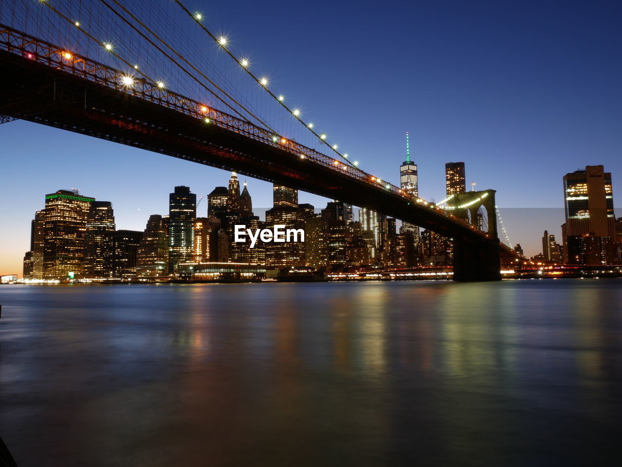 Illuminated bridge over river against sky at night