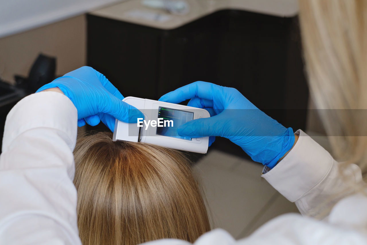 Close up view of the female trihologist examines head skin of woman with special dermatology