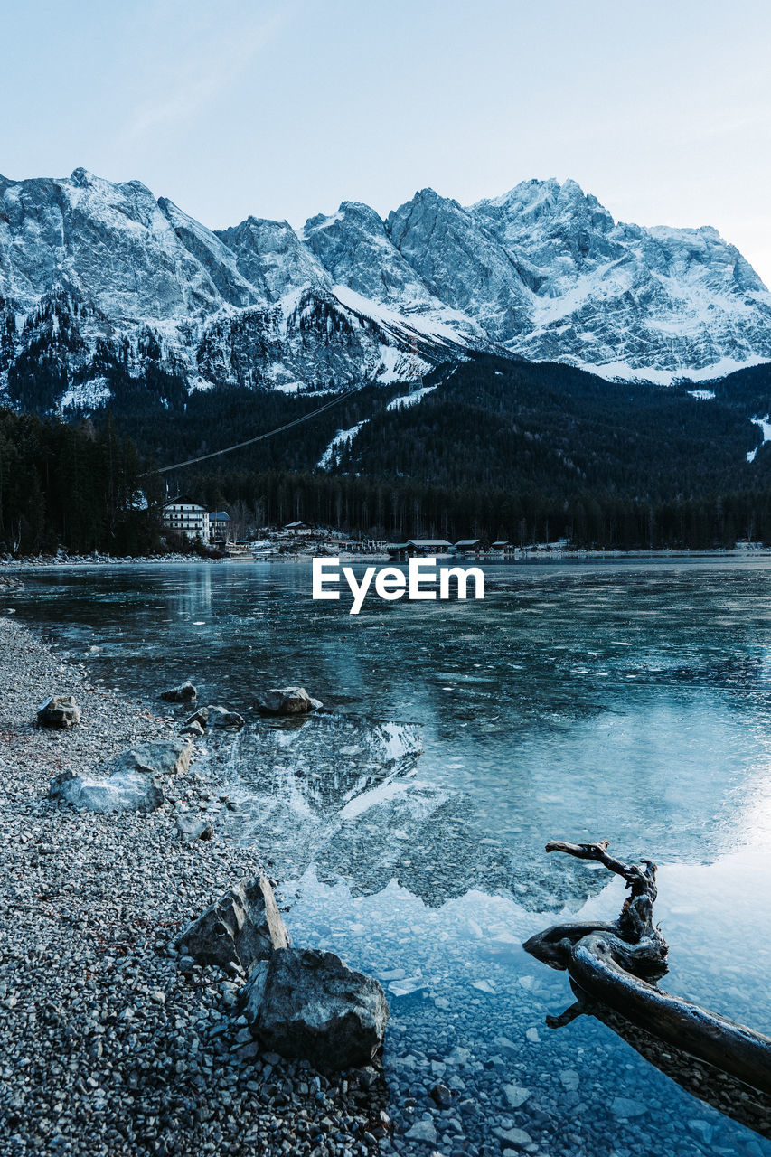 Scenic view of lake by snowcapped mountains against sky