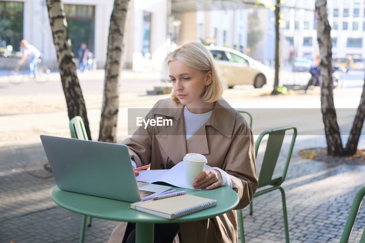 portrait of woman using laptop while sitting on table