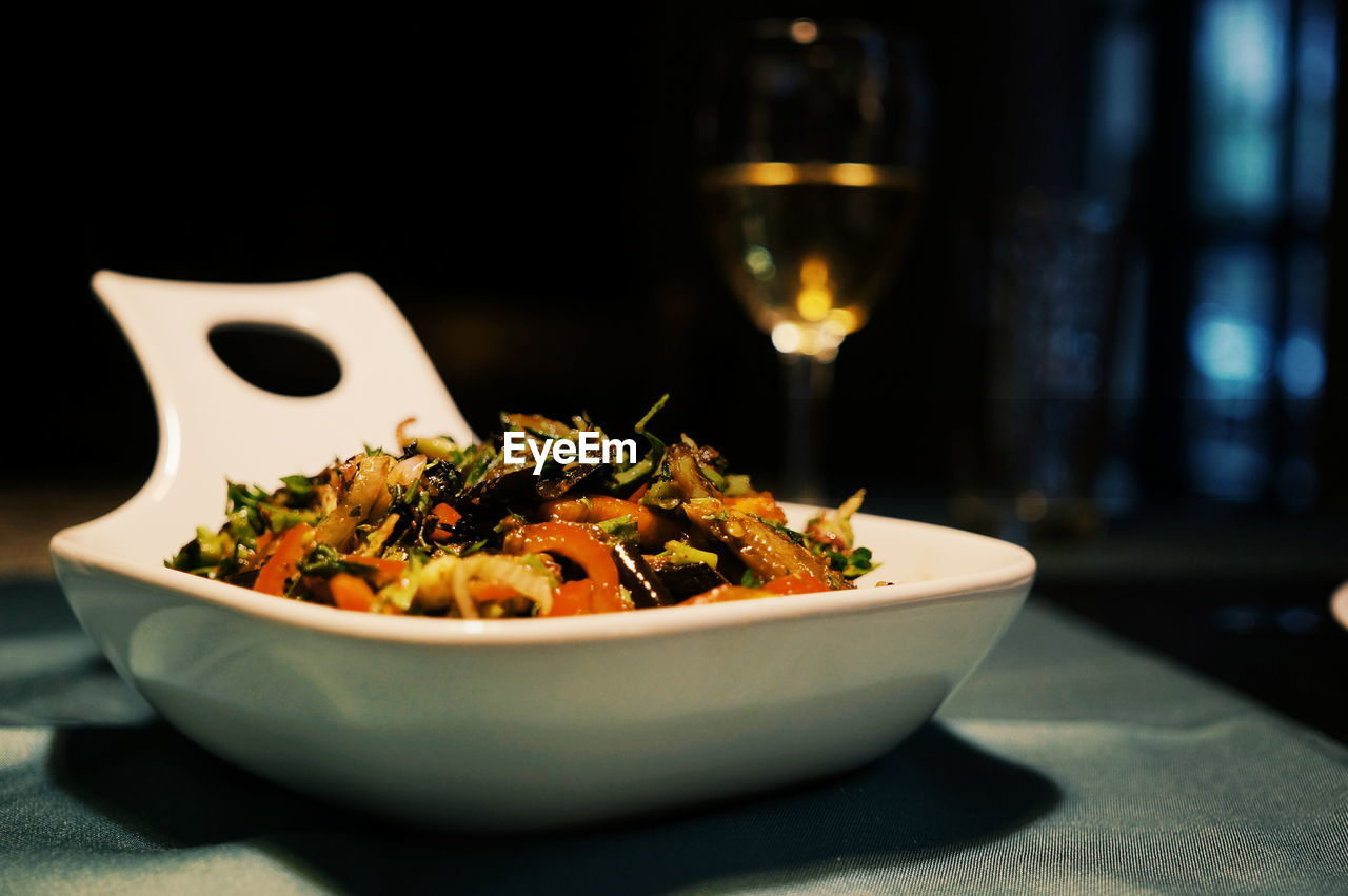 Close-up of vegetarian food in bowl on table with drink glass in background