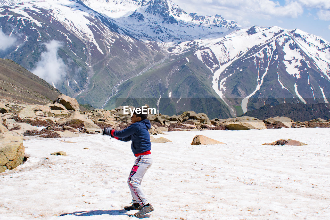 Rear view of boy walking on snowcapped mountain
