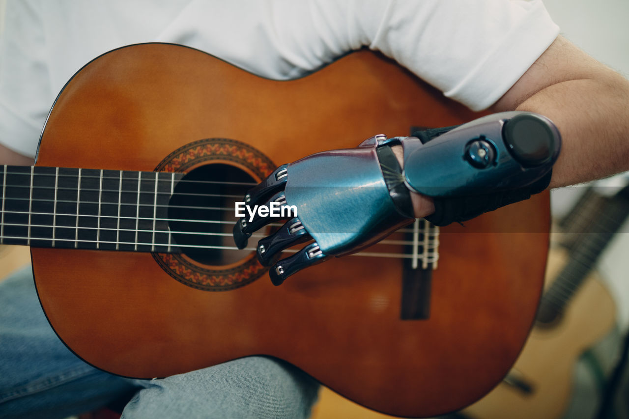 CLOSE-UP OF MAN PLAYING GUITAR IN OFFICE