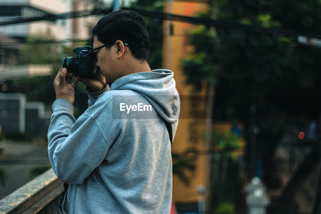 Side view of photographer in hooded shirt photographing