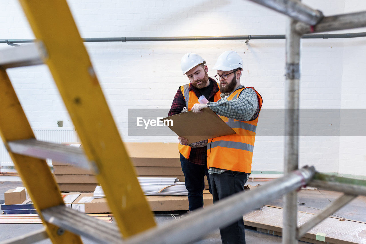 Engineers wearing hardhat having discussion over document