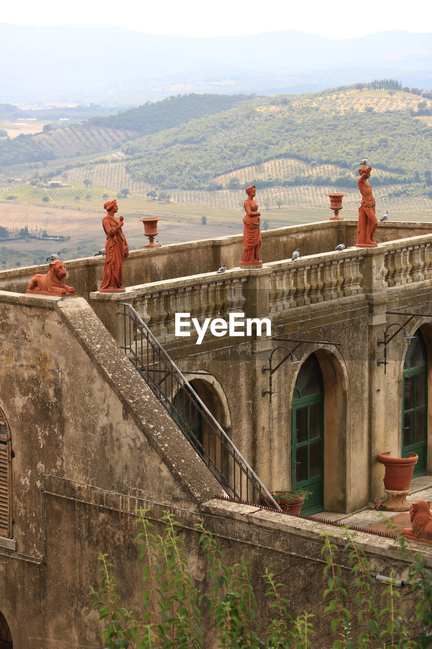 PEOPLE STANDING BY RAILING AGAINST SKY AND MOUNTAIN