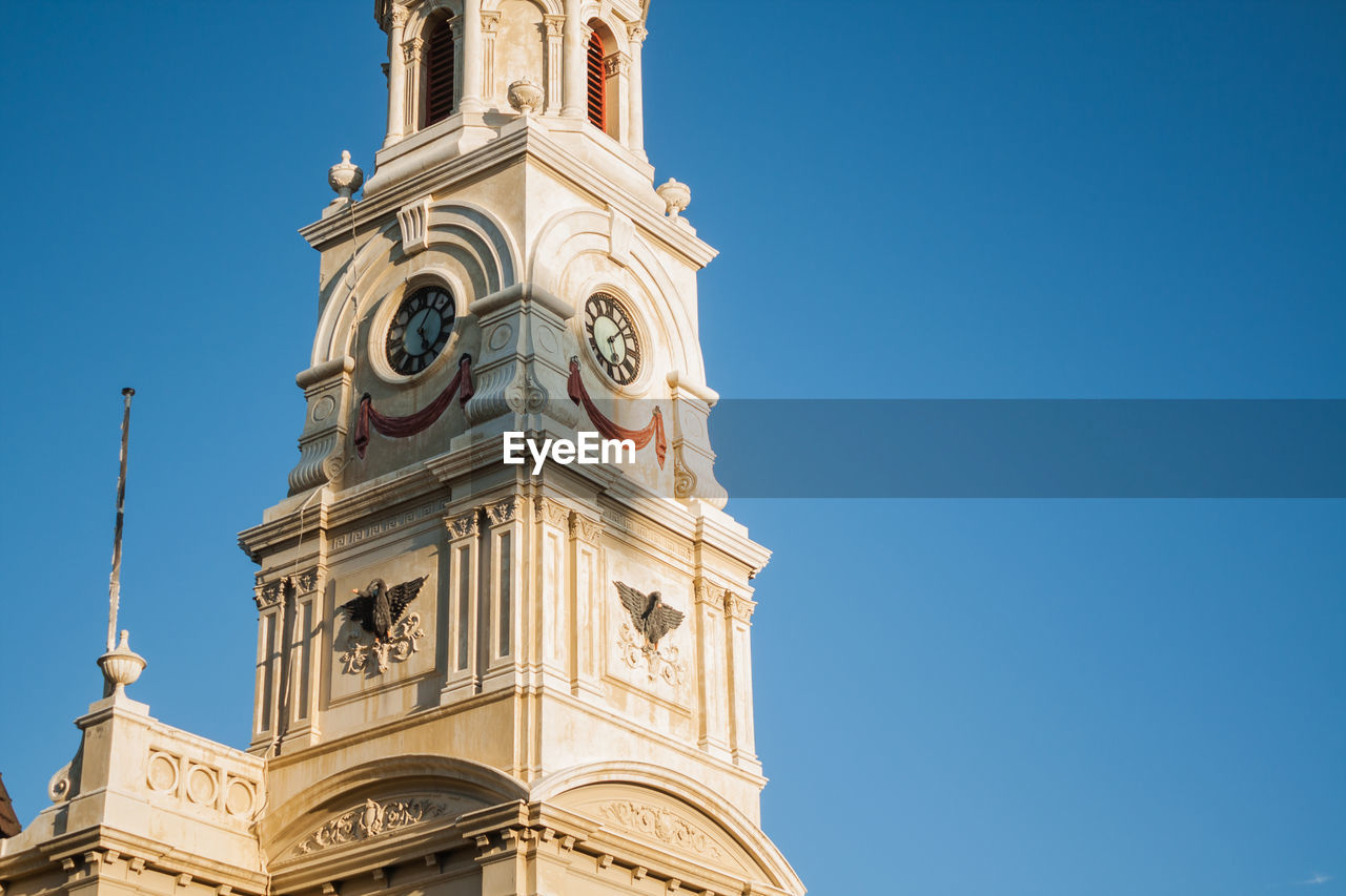 Low angle view of bell tower against clear blue sky