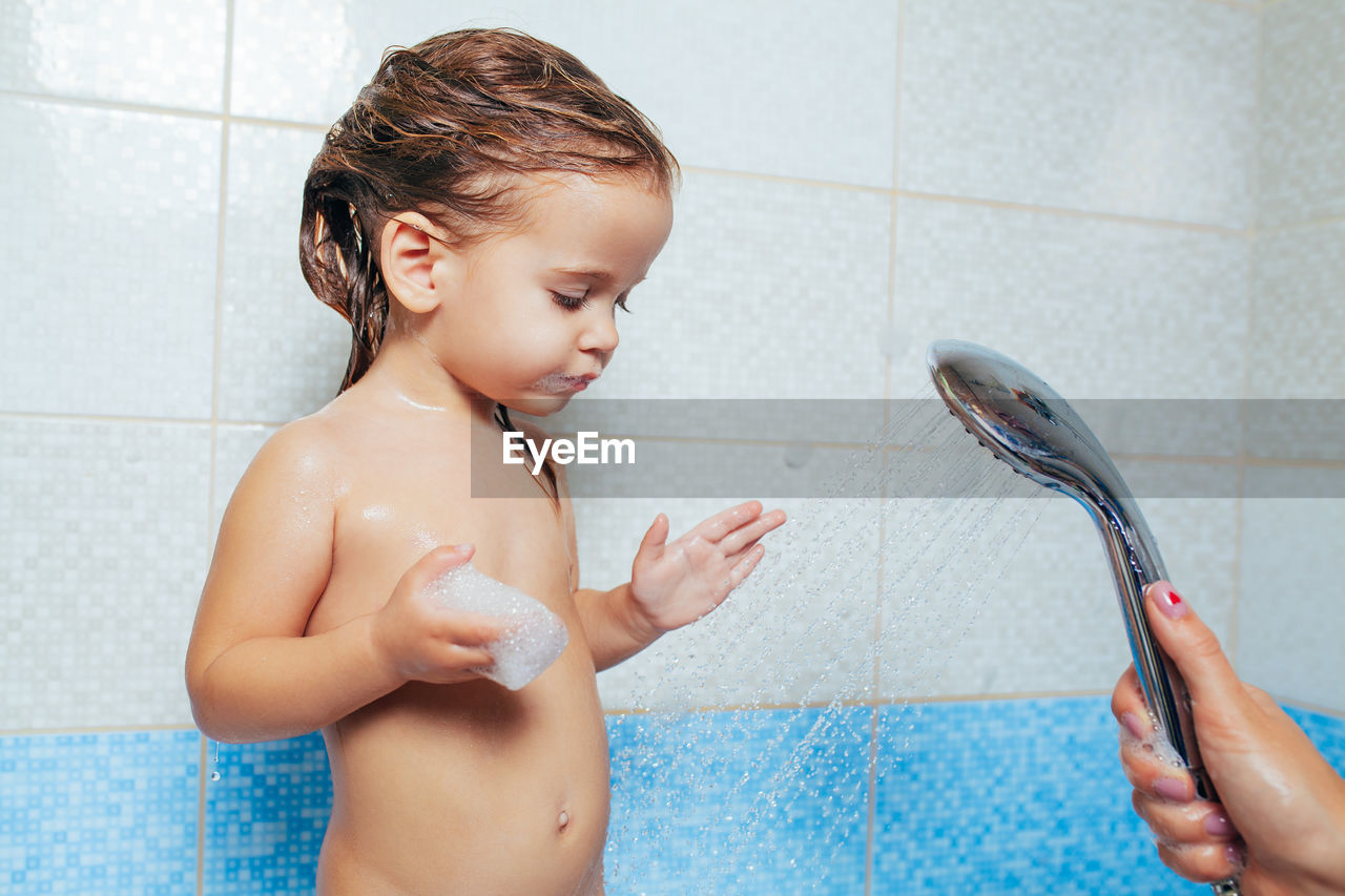 Cropped hands of mother bathing daughter in bathroom