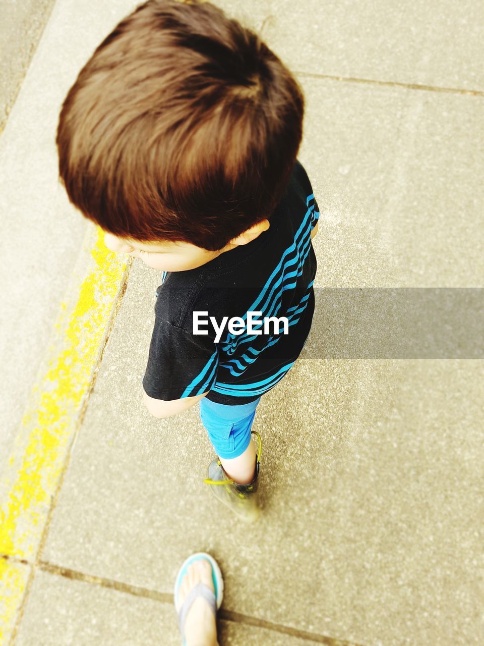 HIGH ANGLE VIEW OF BOY WITH UMBRELLA ON STREET