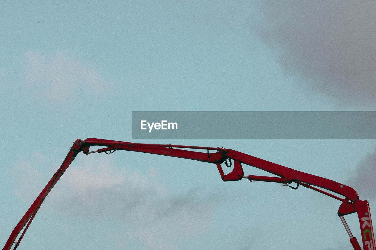 LOW ANGLE VIEW OF RED CRANE AT CONSTRUCTION SITE AGAINST SKY