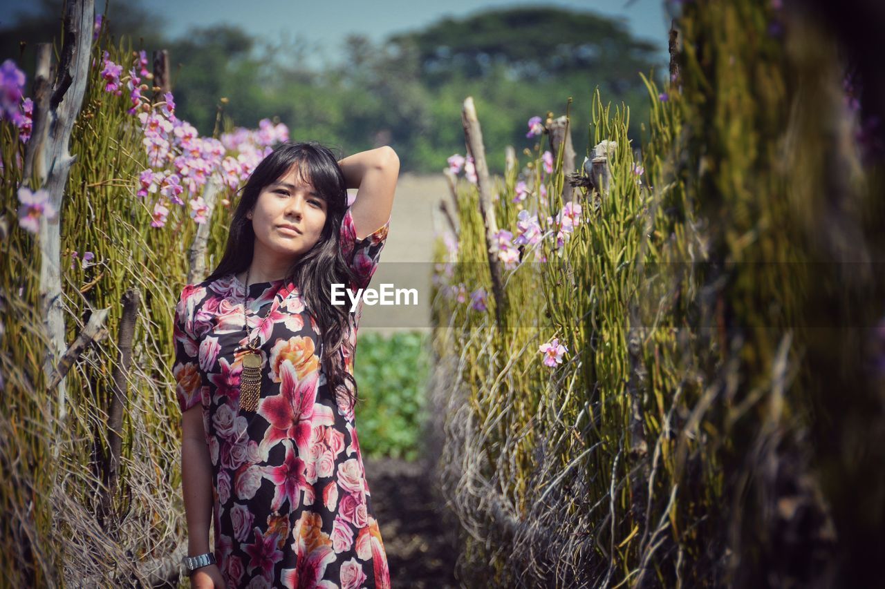 Portrait of woman standing amidst plants on field