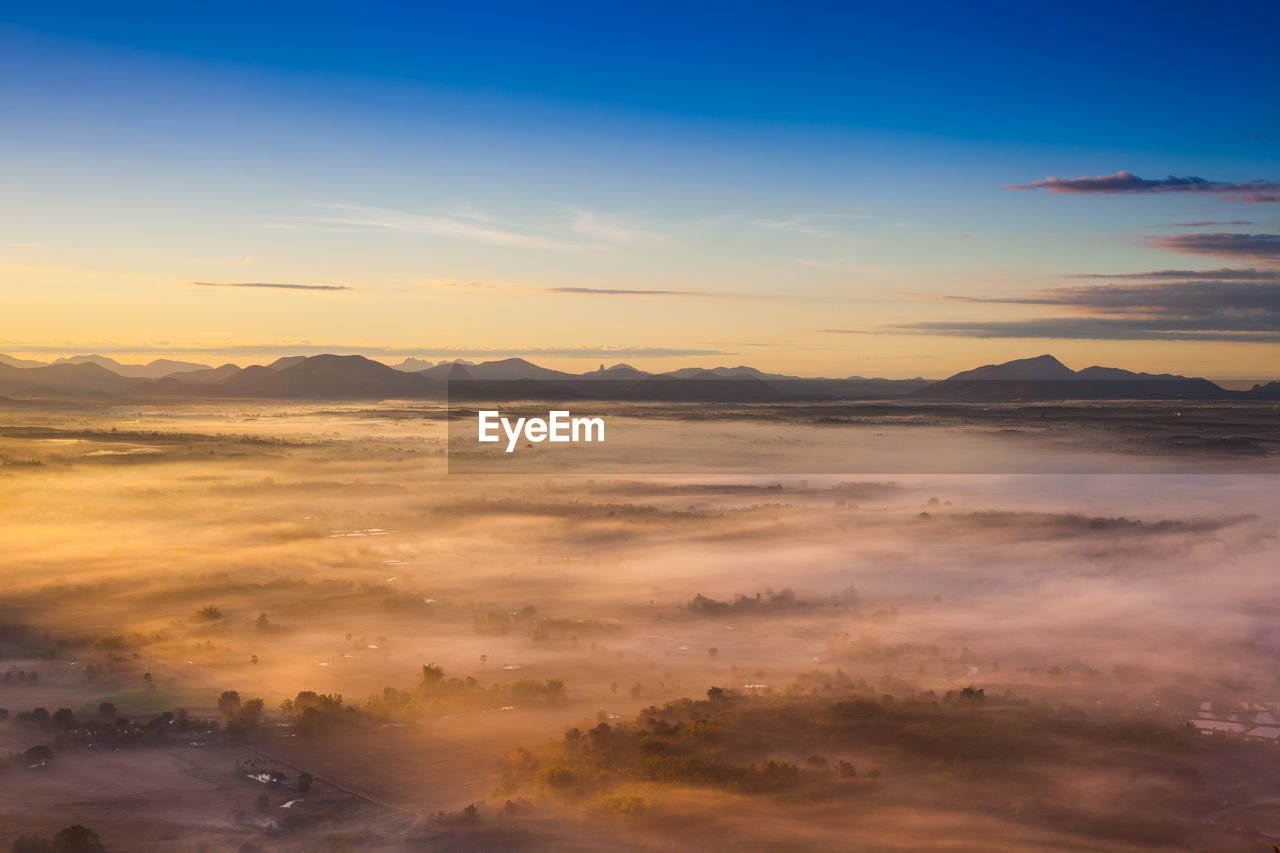 Scenic view of dramatic sky over silhouette landscape during sunset