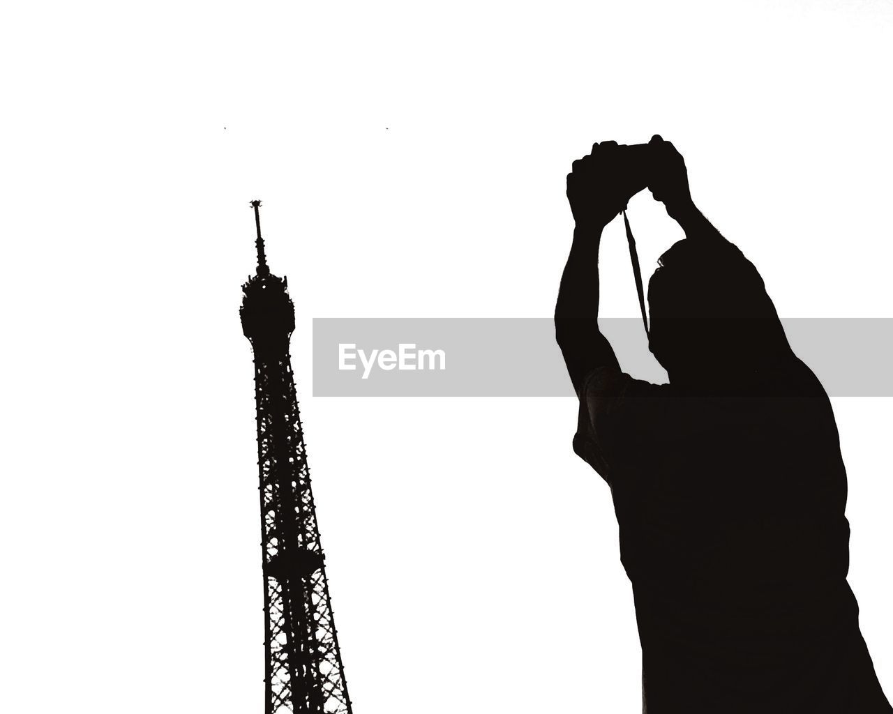 Rear view of silhouette man photographing eiffel tower