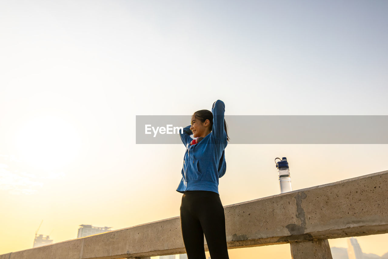 Low angle view of woman standing against clear sky