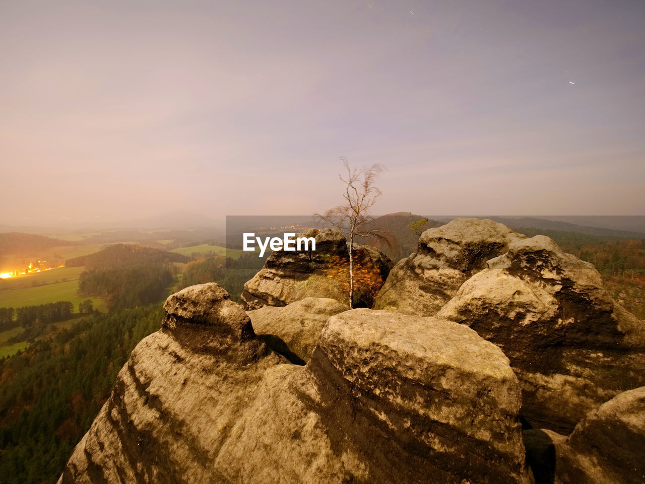 Rocky with tree. full moon night in a beautiful mountain. sandstone peaks and hills in fog is orange