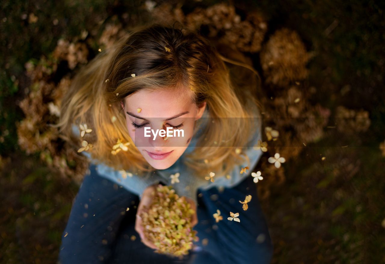 Directly above flowers falling on young woman during autumn