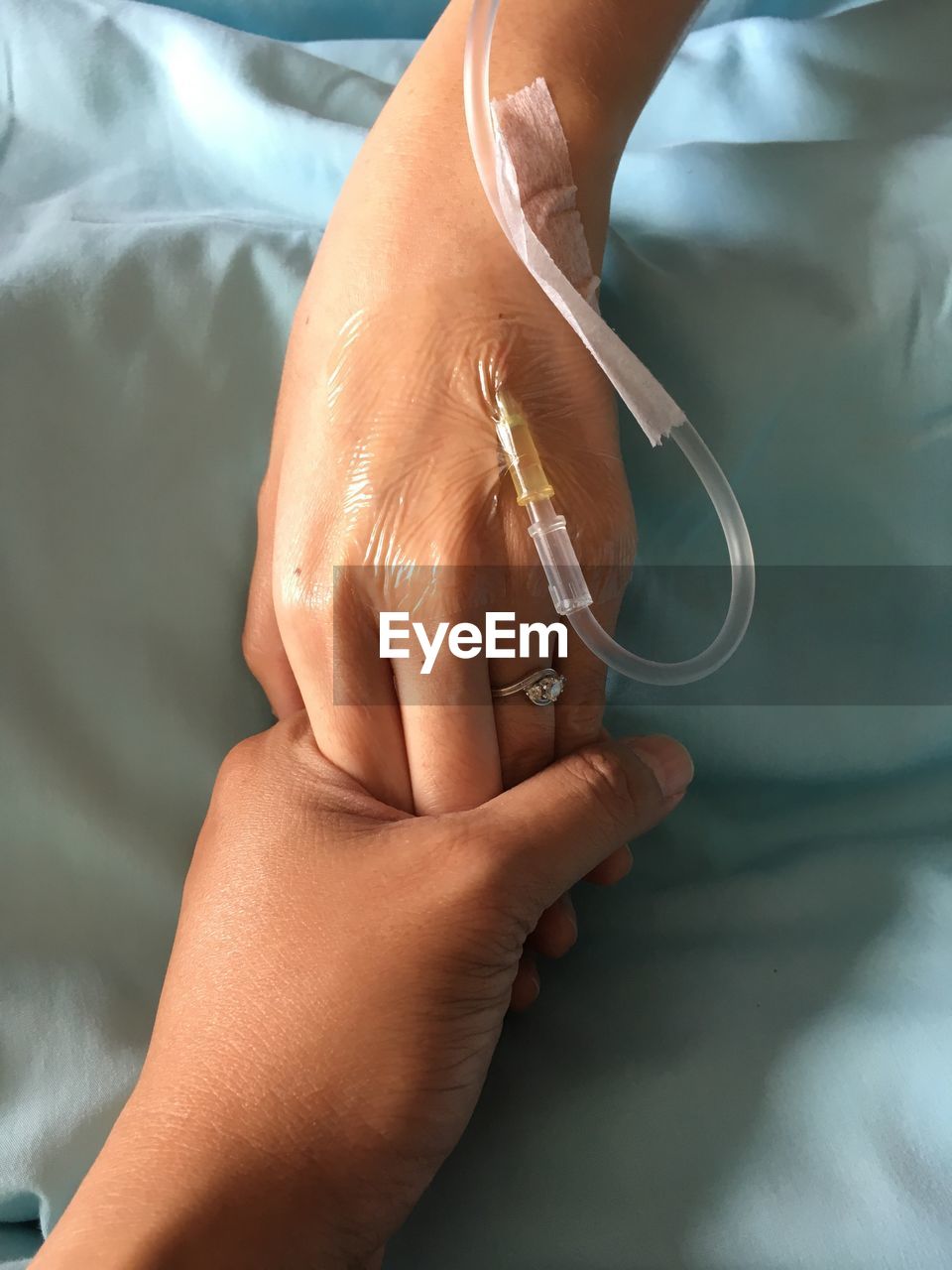Cropped image of woman holding patient hand with iv drip in hospital