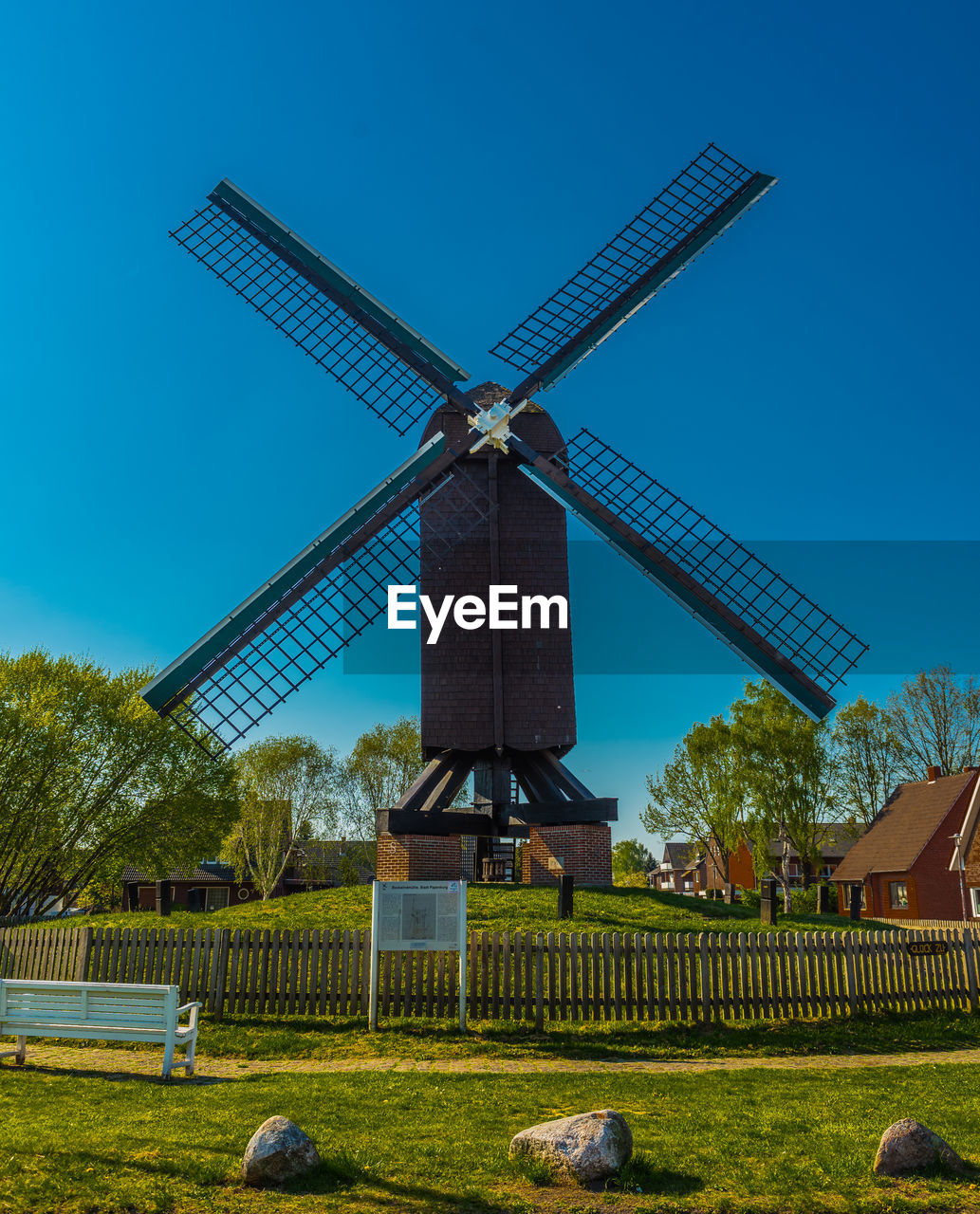 Traditional windmill on field against clear blue sky