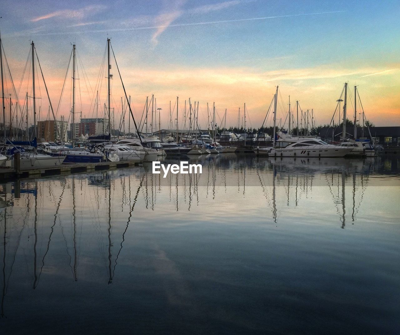 Boats moored at harbor against sky during sunset