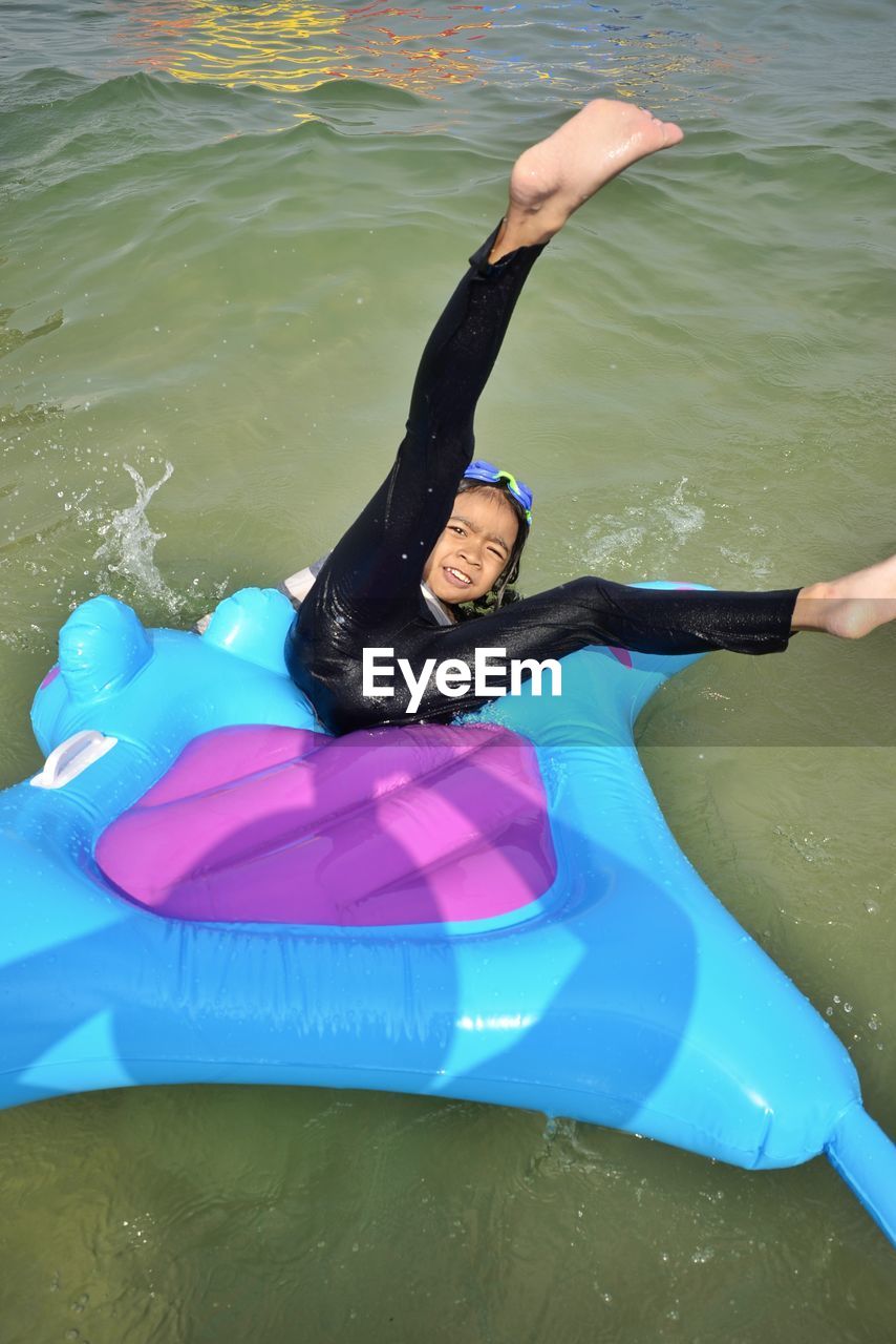 High angle view of girl lying on inflatable raft over lake