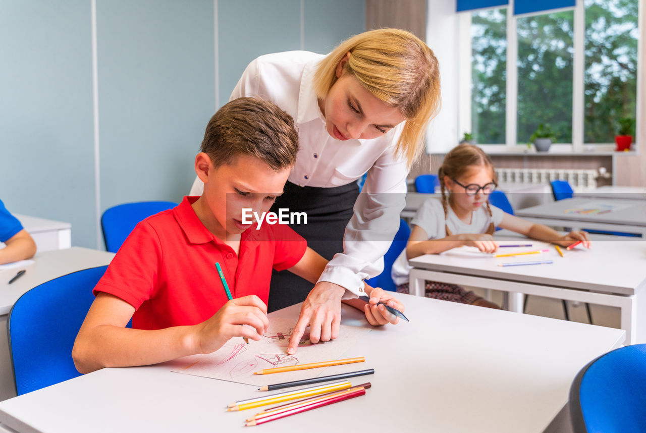 Young teacher teaching student in classroom