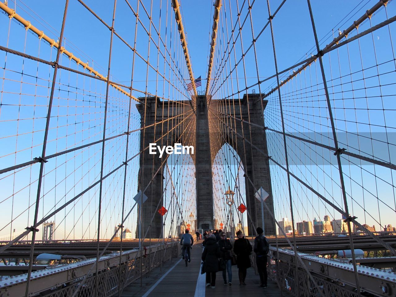 People on brooklyn bridge against clear blue sky