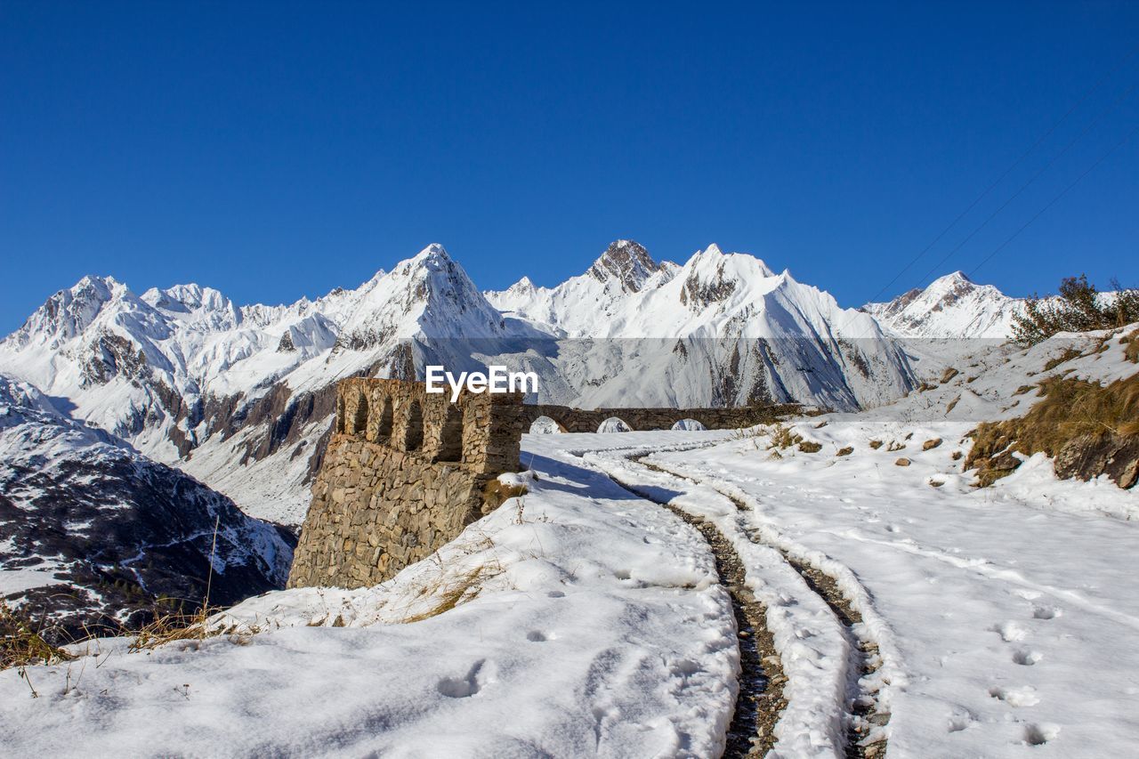 Scenic view of snowcapped mountains against clear blue sky