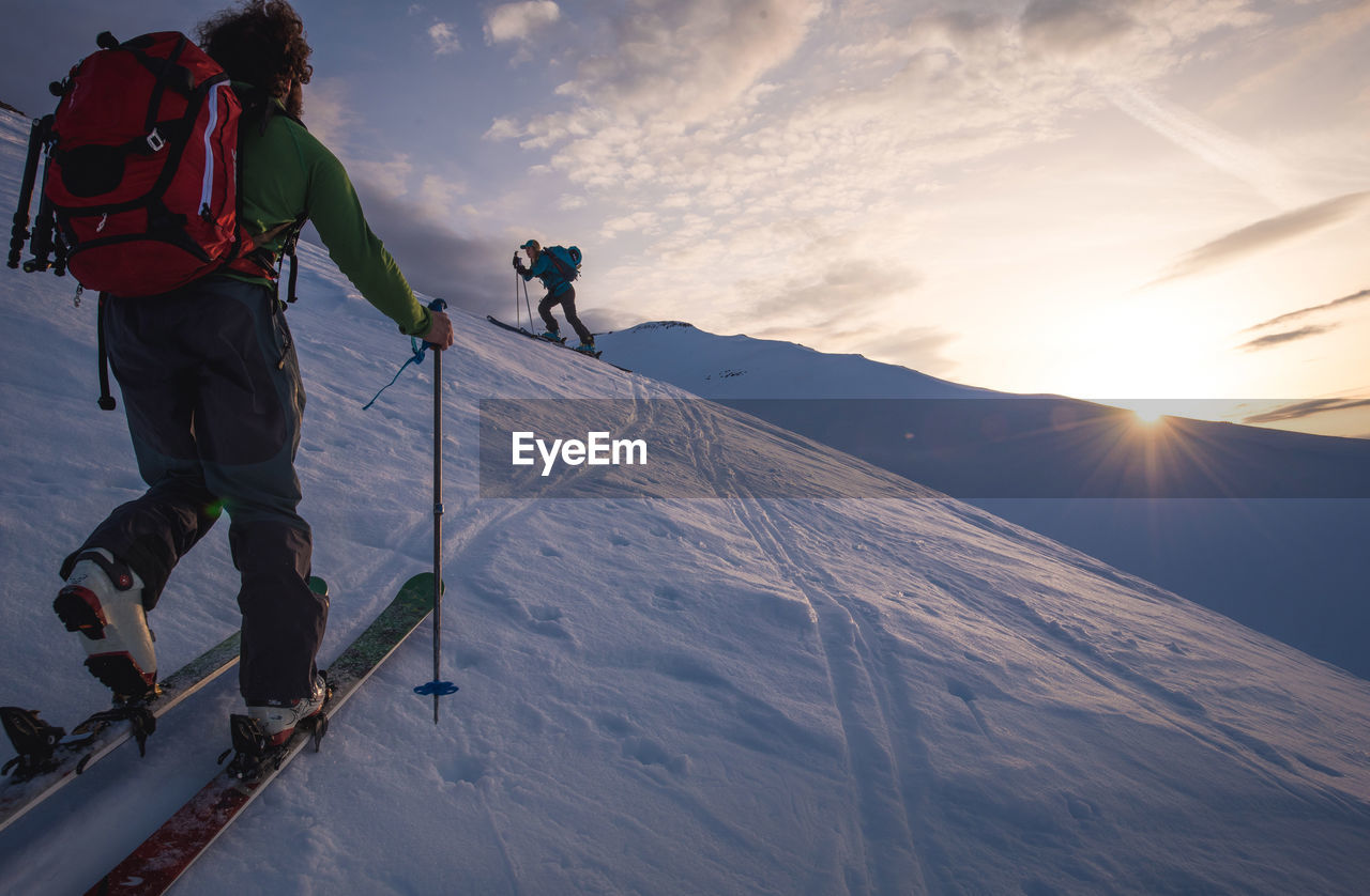 Two people backcountry skiing in iceland at sunrise